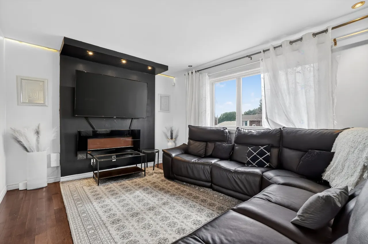 Le salon, son foyer encastré sous le téléviseur et son grand sofa sectionnel